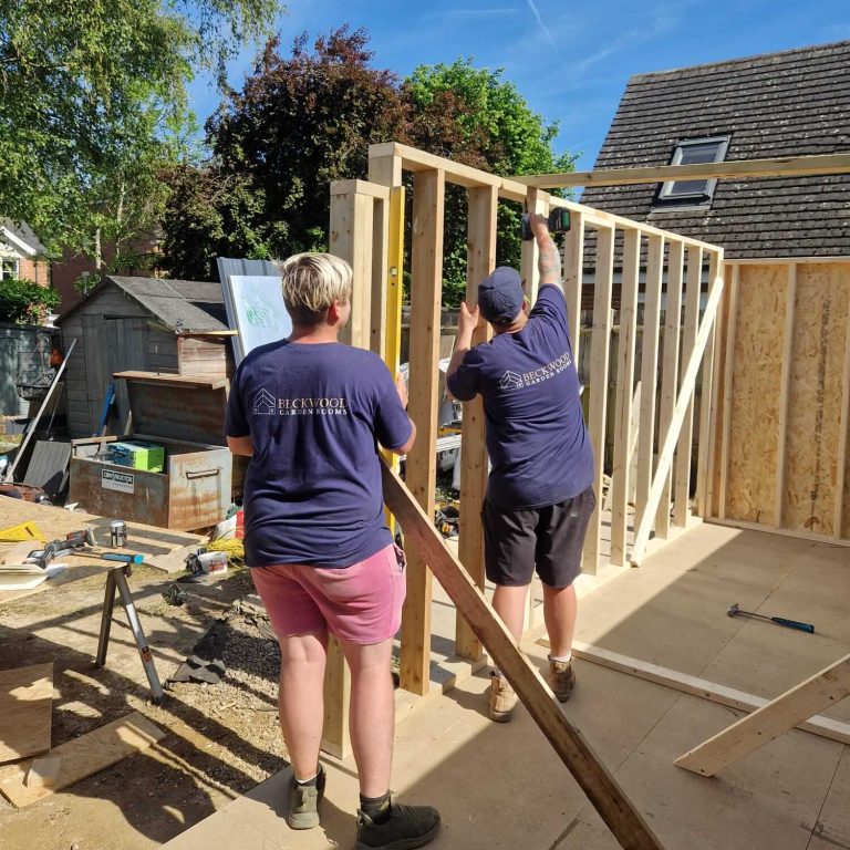 Two Beckwood Garden Rooms team members assembling timber framing during a garden room build.